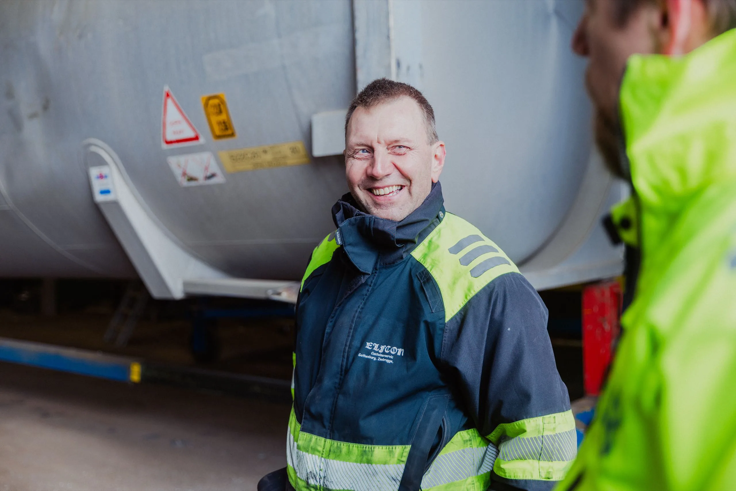 En leende Elfcon-tekniker står bredvid en tankcontainer.